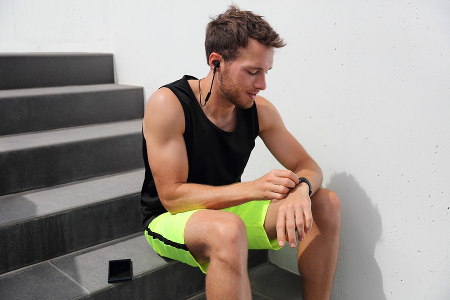 Smartwatch runner man checking progress on smart fitness sport watch during running break after hiit